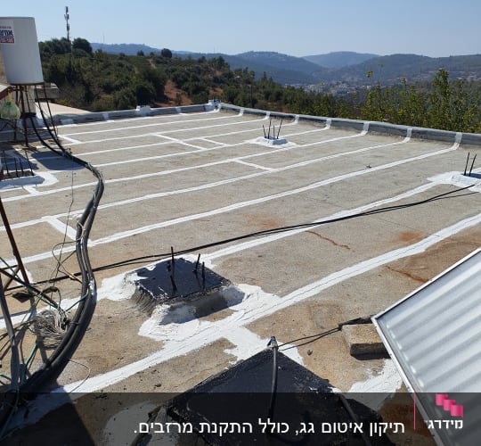 גג עם איטום לבן ושחור, נוף הררי ברקע